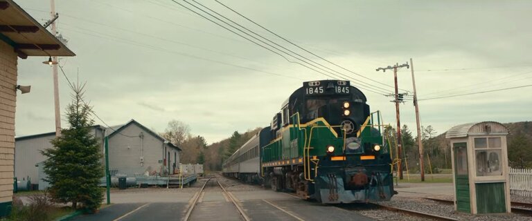 A train (right) approaches the Squahamish railway station, as the train tracks converge to a vanishing point on the horizon.