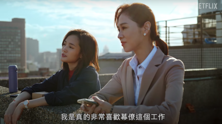 A film still depicting two Taiwanese women talking with each other while standing on a rooftop looking out over Taipei.